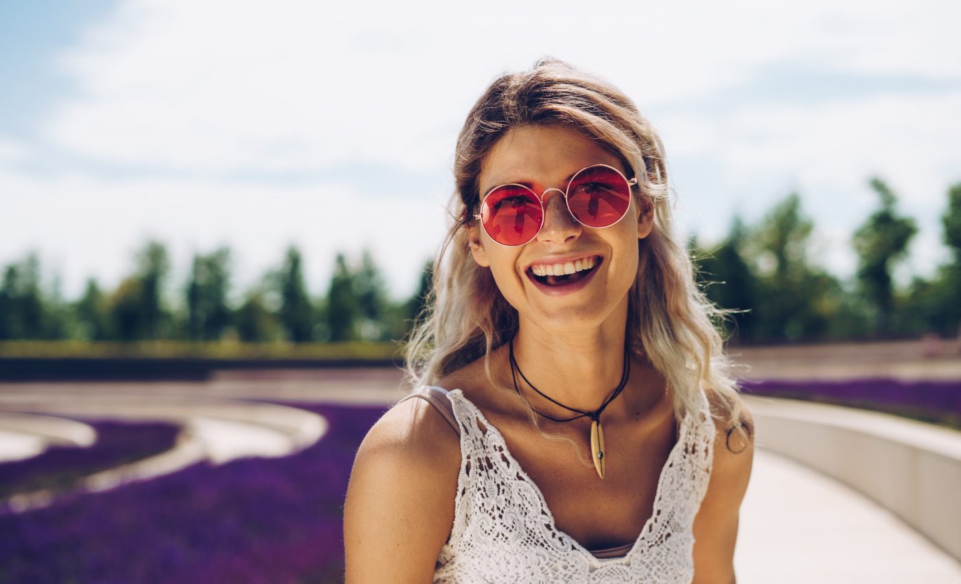 Śmiejąca się kobieta w białej sukience i różowych okularach