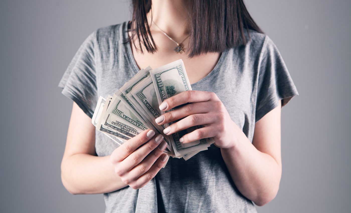 Kobieta w szarej bluzce trzymająca plik banknotów