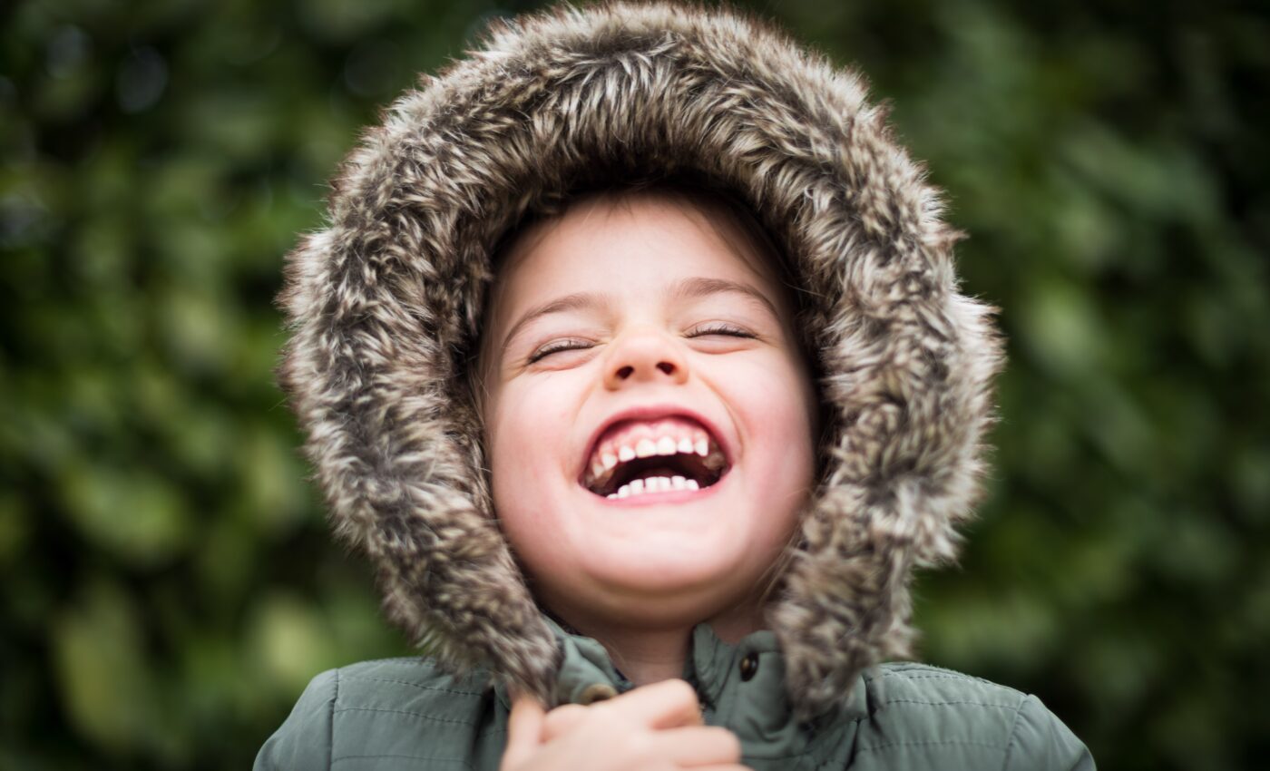 Śmiejący się chłopies z założonym na głowę kapturem obszytym futerkiem