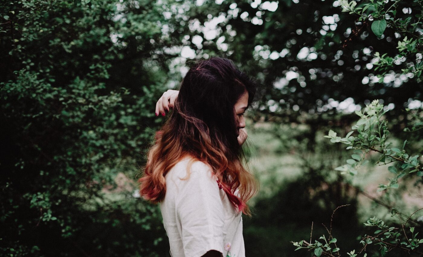 Kobieta w białej bluzce w otoczeniu zieleni