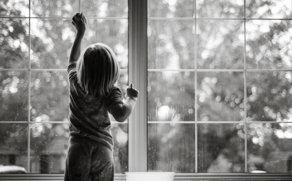 Mała dziewczynka sprząta myjąc okno.