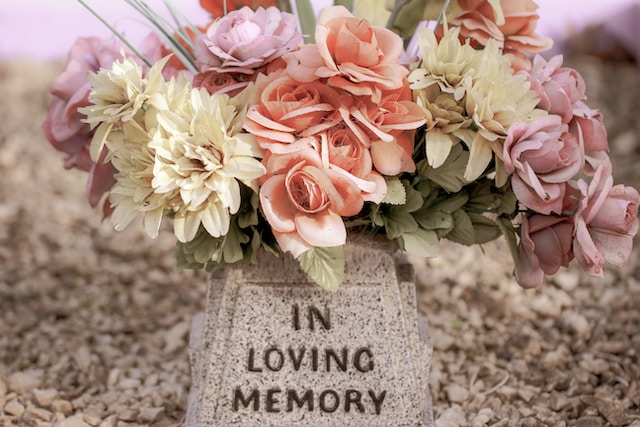 Bukiet wyblakłych sztucznych kwiatów leżących na nagrobku