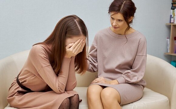 Płacząca kobieta w kremowej sukience szuka pomocy psychologa