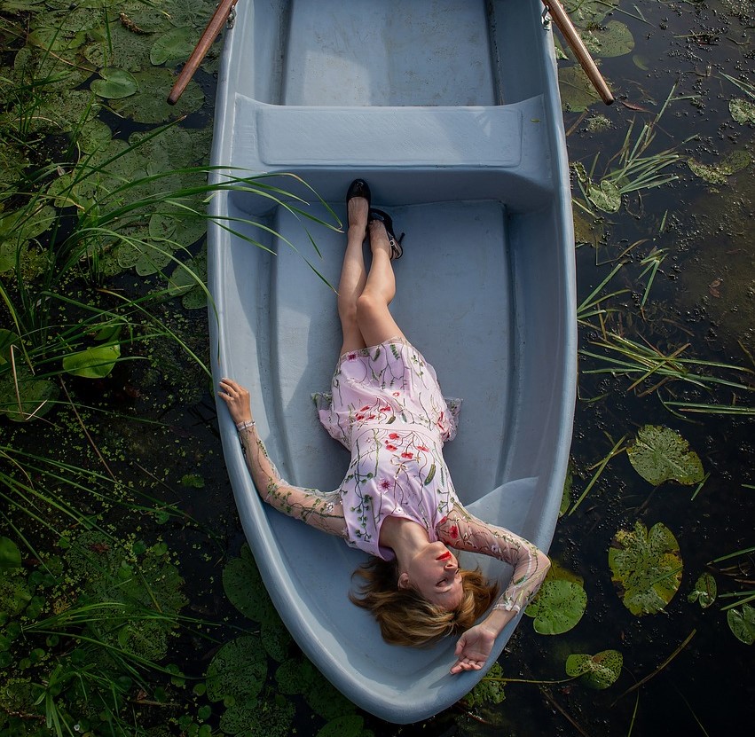 Leżąca kobieta na łódce znajdującej się na wodzie