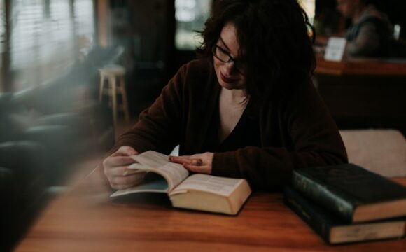 Kobieta w brązowej bluzce czyta książkę, efektywnie się ucząc
