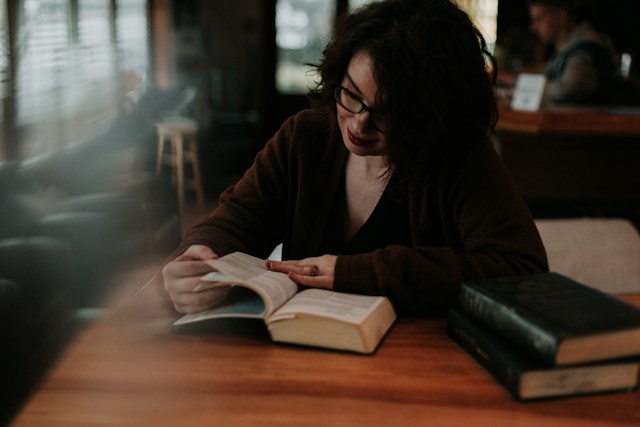 Kobieta w brązowej bluzce czyta książkę, efektywnie się ucząc