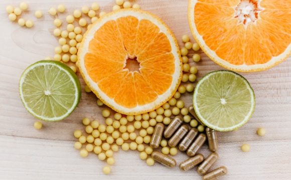 Na stole leżą tabletki i przekrojone na pół pomarańcze i limonki.