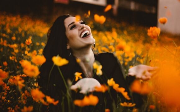 Uśmiechnięta brunetka wśród żółtych kwiatów