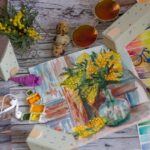 Stół, na którym znajduje się namalowany obraz żółtych kwiatów w wazonie