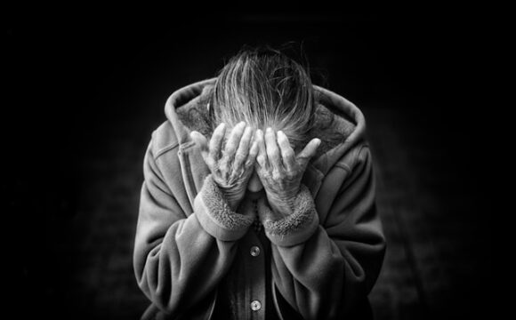 Czarno-białe zdjecie kobiety zakrywającej twarz