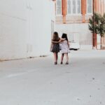 Dwie dziewczynki idące chodnikiem i obejmujące się ramionami