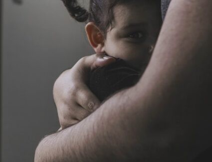 Smutny chłopiec szukający wsparcia w ramionach dorosłego