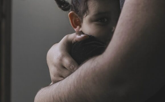 Smutny chłopiec szukający wsparcia w ramionach dorosłego