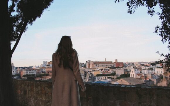 Kobieta w płaszczu patrzy na miasto