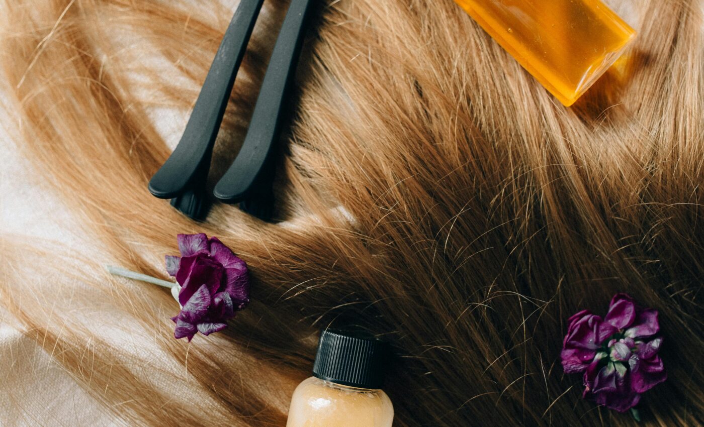 Rozpuszczone włosy rozłożone na białym tle, a na nich leżą kosmetyki