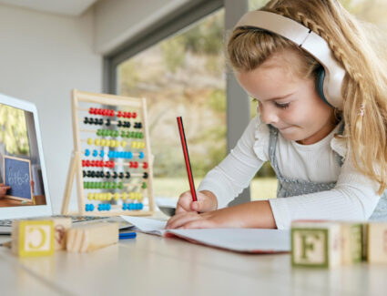 Małą dziewczynka ze słuchawkami uczy się matematyki online