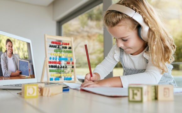 Małą dziewczynka ze słuchawkami uczy się matematyki online