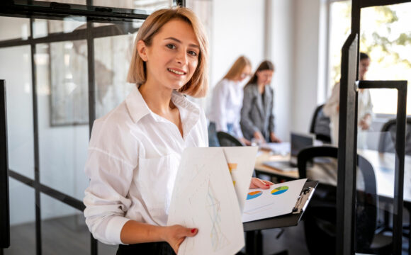 Kobieta w białej koszuli trzyma w rękach plik dokumentów