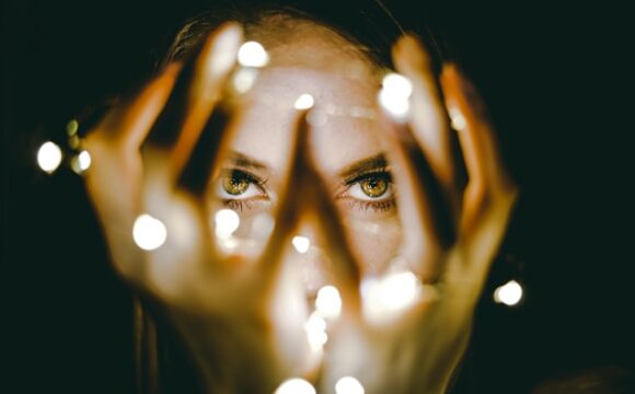 Kobieta trzymajaca w dłoniach zapalone lapmki