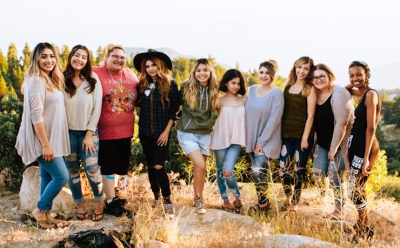 Grupa kobiet obejująca się i stojąca na wzgórzu