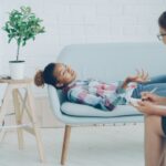 Kobieta w koszulu w kratkę leży nabiałej sofie u teraputy