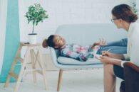 Kobieta w koszulu w kratkę leży nabiałej sofie u teraputy