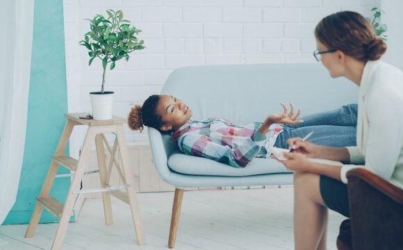 Kobieta w koszulu w kratkę leży nabiałej sofie u teraputy