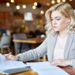 Kobieta w szarej marynarce przegląda dokumenty