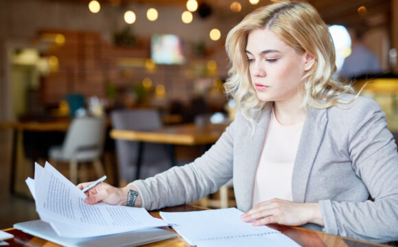 Kobieta w szarej marynarce przegląda dokumenty
